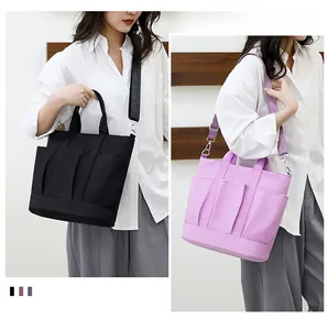 Detail of large capacity nylon tote bag with multiple front pockets in black and purple