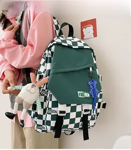 Detail view of checkerboard backpack showing front pocket with fashion label and bunny charm