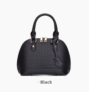 Close-up of black shell handbag with crocodile texture and gold dual zippers