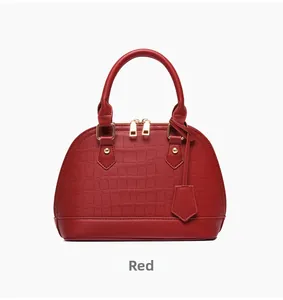 Detailed view of red shell handbag with crocodile texture and gold dual zippers