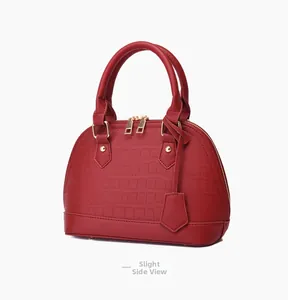Side view detail of red crocodile embossed shell bag with gold hardware and studs