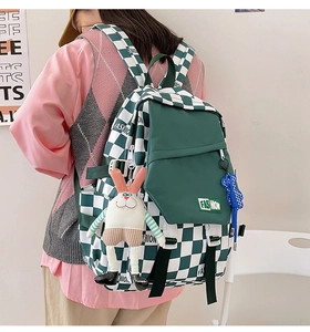 Detail of green checkerboard backpack with cartoon rabbit charm and fashion label