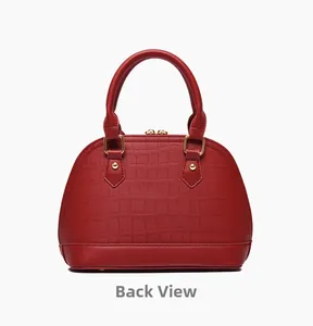 Detail view of red crocodile textured shell handbag featuring gold zippers and sturdy handles