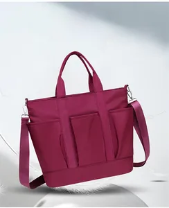 Detail of lightweight burgundy nylon tote bag with chic buckle opening and storage pockets