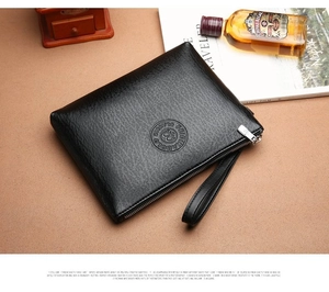 Detail of black lychee grain leather clutch featuring embossed logo and silver zipper