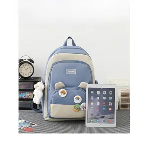 Blue and beige school backpack with bear ears and badges shown next to an iPad for size
