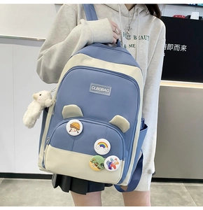 Detail of blue and beige school backpack with cute cartoon badges and sheep plush pendant