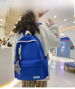Détail d'un sac à dos en nylon bleu montrant le compartiment principal et le charme en damier