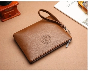 Gros plan sur la pochette pour hommes en cuir marron avec logo et fermeture éclair