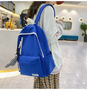 Gros plan d'un sac à dos en nylon bleu vif avec liseré blanc et breloque en damier