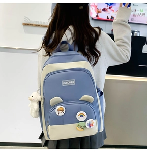 Close-up of blue and white school backpack with cute plush lamb and cartoon pins