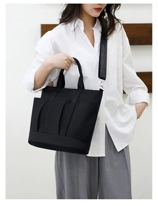 Close-up of black nylon tote bag with multi-pockets and detachable shoulder strap on model