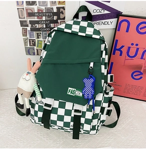 Detail view of green checkerboard backpack with fashion label and plush charms