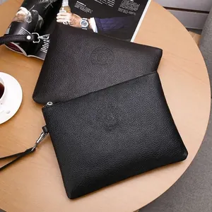 Men's business clutch bag in black and coffee leather with litchi texture on a wooden table