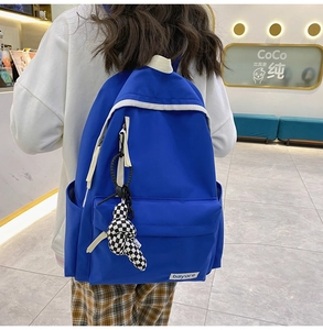 Détail du sac à dos en nylon bleu vif avec fermetures blanches et pendentif damier