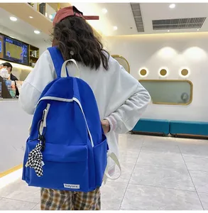 Détail du sac à dos en toile bleue avec pendentif ours et sangles contrastées blanches