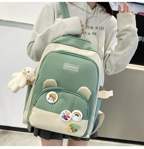 Detail of light green campus backpack with cute cartoon badges and bear keychain
