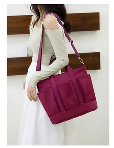 Detail of burgundy nylon tote bag showing multiple front pockets and adjustable strap