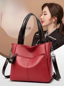 Detail view of red faux leather tote bag with lychee grain texture and brown handles