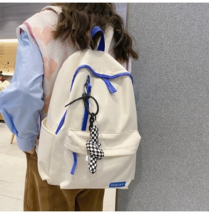 Vue détaillée du sac à dos en nylon crème avec finitions bleues et charme en damier