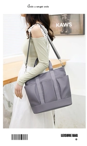 Close-up of grey nylon tote bag with three front pockets and adjustable shoulder strap