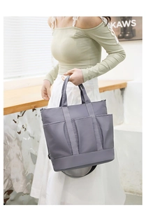 Detailed shot of a grey nylon tote bag featuring three front pockets and metal buckle