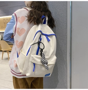 Détail d'un sac à dos en nylon crème et bleu avec un pendentif lapin à carreaux tendance