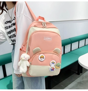 Detail of pink and white patchwork backpack with cute cartoon badges and bear pendant
