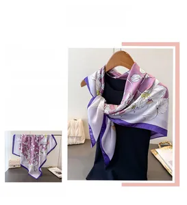Détail de la texture en soie lisse et du motif floral violet sur l'écharpe