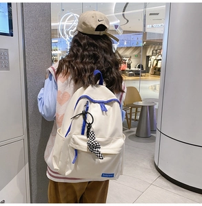 Détail d'un sac à dos en nylon crème avec accents bleus et un pendentif à damier élégant