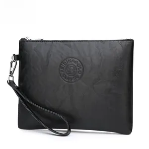 Detail of black leather clutch bag showing pebbled texture and silver zipper with wrist strap