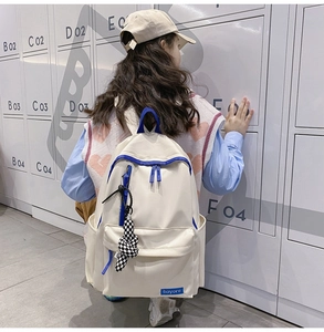 Détail du sac à dos en nylon blanc avec garniture bleue et pendentif à damier