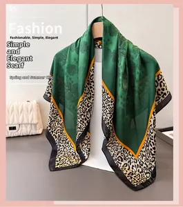 Dettaglio foulard in seta verde con motivi floreali, bordi leopardati e strisce gialle