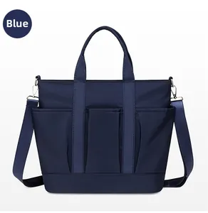 Detail of dark blue nylon tote bag showing front pockets and detachable shoulder strap