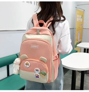 Pink and beige student backpack with cute bear ears and character pins shown on model