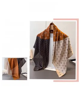 Dettaglio di sciarpa effetto seta con motivi geometrici in arancio, caffè e beige