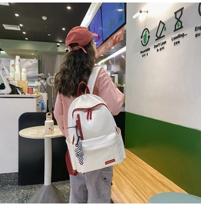 Vue arrière d'un sac à dos en nylon beige avec détails rouges et charme à damier