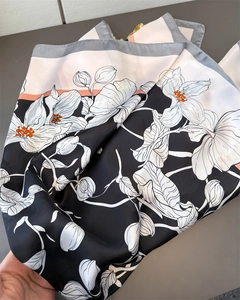 Détail d'un foulard en soie avec imprimés floraux linéaires et bordures bicolores élégantes