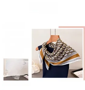 Detailed pattern of silk scarf featuring golden chain print and herringbone texture
