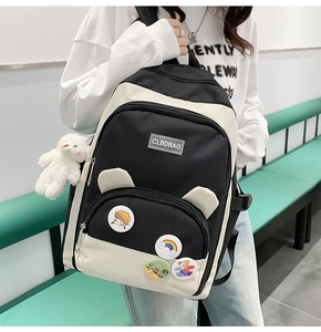 Detail of black and white canvas backpack featuring cartoon badges and plush bear charm
