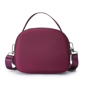 Borsa impermeabile in nylon bordeaux con ampia tracolla su sfondo bianco neutro