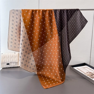Elegante foulard quadrato in raso con motivi geometrici e pois appeso a un supporto