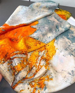 Close-up of glossy ink-wash print silk scarf with fine rolled edges and vibrant abstract art