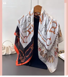 Detail of silk satin scarf with classic chain and tassel print on a wooden hanger