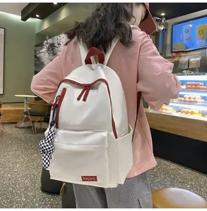 Détail du sac à dos en nylon blanc avec zips rouges et pendentif en damier noir et blanc