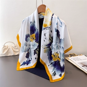 Detail of silk-like floral square scarf with royal blue flowers and yellow rolled edges