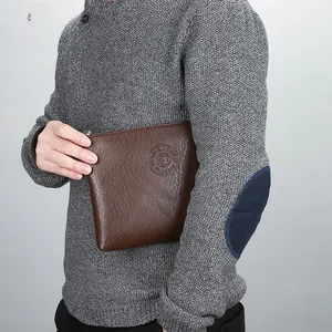 Brown textured leather clutch bag for men held by model to show size and style