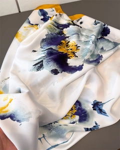 Detail of silk-like scarf featuring artistic blue and yellow floral ink patterns