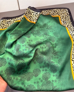 Dettaglio di sciarpa satinata con stampe floreali verdi e bordo leopardato giallo