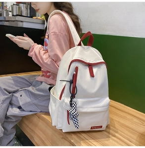 Détail du sac à dos en nylon blanc avec finitions rouges et accessoire à damier